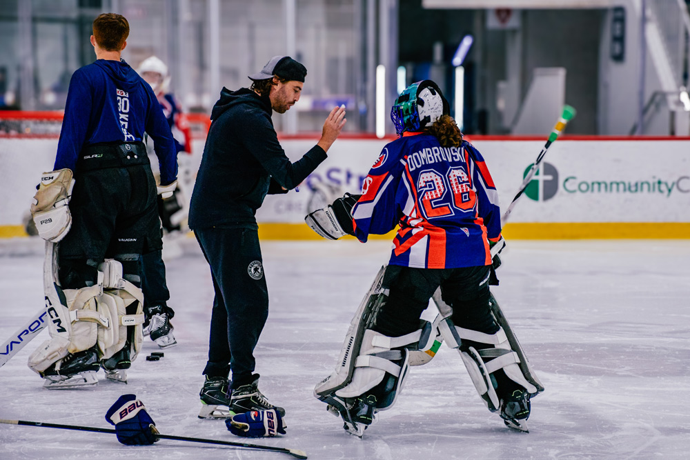 Young goalies in a coaching huddle on the ice